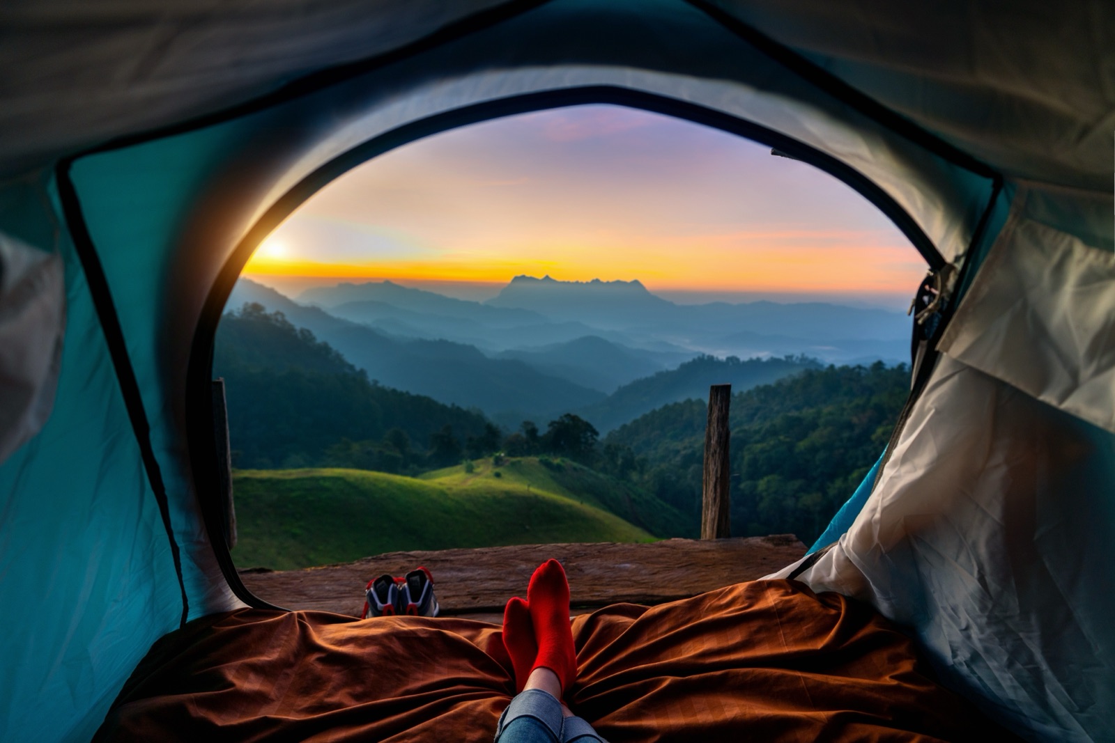 Sunrise over mountain ridges seen from inside a tent